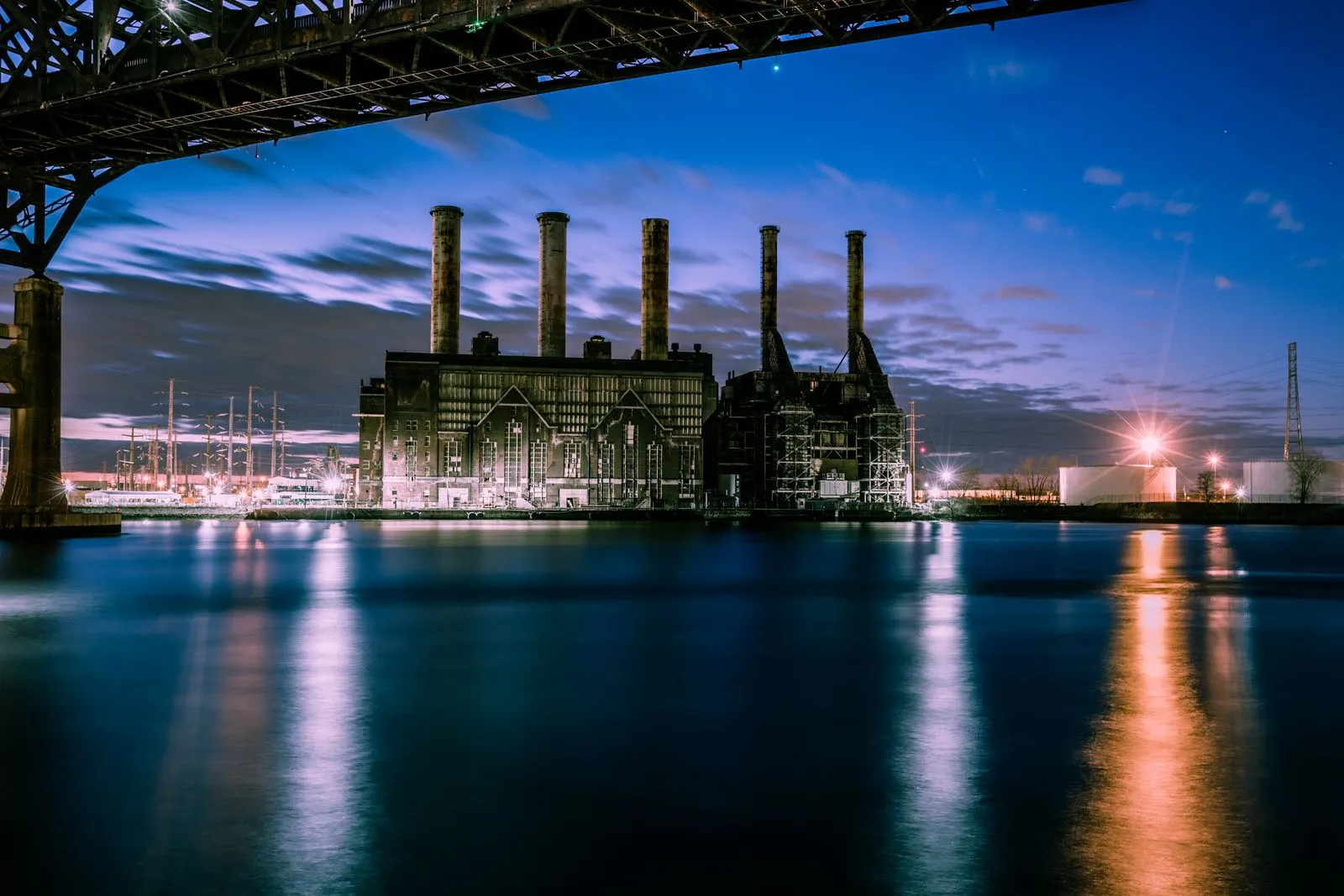 A power generating station silhouetted against a twilight sky, reflected in the water
